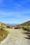 Dirt road leading toward valley beyond under a blue sky