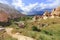 A dirt road meanders between conical peaks of rocks, ancient caves against the backdrop of the mountain landscape of the valley in