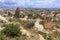 A dirt road meanders between conical peaks of rocks, ancient caves against the backdrop of the mountain landscape of the valley in