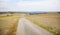 Dirt road in the middle of a mown wheat field, large areas of stubble visible.