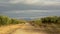 Dirt road in between olive orchards in Sierra Nevada mountains under a cloudy evening sky,