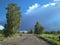 Dirt road travel for cars in summer with trees stormy sky with clouds