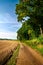 Dirt track road next to forest and plowed field. Calm and silence of countryside.