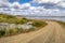 Dirt winding road along the Tom river in Siberia in autumn under a cloudy sky