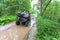 Dirty ATV stands with bags and stuff in the deep muddy puddle on the forest road