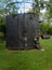 Dirty black storage tank for oil on a green lawn