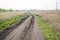 Dirty broken dirt road among the fields in early spring. The concept of travel