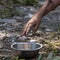 A dirty children`s hand reaches for a metal plate standing on the ground. The concept of slavery, hunger, violence and child