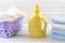 Dirty cloth in a plastic purple laundry basket, clean folded cloth and blank yellow detergent bottle on white wood background