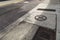 Dirty concrete and brick sidewalk alongside a street, turn lane arrow and streetcar rails, metal grate and manhole, Georgia USA