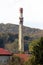 Dirty concrete tall red and white rectangle industrial chimney with two metal safety platforms and multiple cell phone antennas