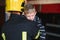 Dirty firefighter in uniform holding little saved boy standing on black background.