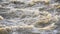 Dirty flood water flowing rapidly in river, closeup abstract detail, slow motion video