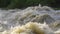 Dirty flood water flowing rapidly in river, closeup abstract detail, slow motion video