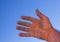 Dirty hand hardened by work stands on a blue sky