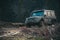 Dirty offroad car with dark forest on background, defocused.