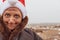 A dirty poor homeless woman in a New Year`s hat smiles against the background of a dump