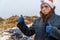 Dirty poor homeless woman in a New Year`s hat, unsure of herself, shows a thumb up class against the background of a dump