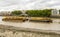 Dirty shores of river Thames and rusty barges loaded with containers near Cringle Dock Solid Transfer Station, London, England