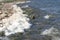 Dirty textured foam surface made by waves of water. Closeup view of abstract shore of a lake, river or sea. Concept of nature