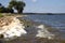 Dirty textured foam surface made by waves of water. Closeup view of abstract shore of a lake, river or sea. Concept of nature