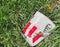 Dirty thrown KFC branded paper bucket laying on grass. Environment pollution issues.