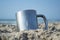 Dirty tourist metal cup in the sand by the sea