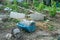 Dirty watering pot on the ground at the backyard of house with blurred vegetable farm in background