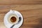 A dirty white coffee cup stands on a wooden table. Leftover breakfast