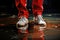 Dirty white sneakers on the feet of a man in red trousers walking through a puddle, close-up