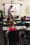 Disable schoolgirl with classmate studying in classroom sitting at desk of elementary school