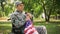 Disabled american veteran putting flag to heart remembering war, faith and pride