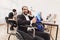 Disabled arab man in wheelchair working in office. Man is talking on phone and drinking coffee.