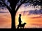 Disabled blind with cane and dog under tree near sea sunset