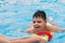 disabled boy with a float laughs as he plays and swims in a pool with his father