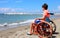 Disabled boy sitting in a wheelchair looks at the sea