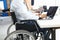 Disabled businessman sits in wheelchair in office and works at laptop