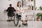 Disabled businesswoman sitting in wheelchair with crossed arms near collegue working on background