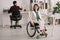 Disabled businesswoman sitting in wheelchair in office near colleague