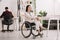 Disabled businesswoman sitting in wheelchair in office near colleague