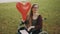 Disabled caucasian young woman with red balloon having fun in nature