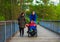 Disabled child in wheelchair at park with father and sister