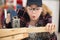 disabled female carpenter blowing dust from wood