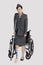 Disabled female US military officer with crutch standing in front of wheelchair over gray background