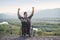 Disabled guy sitting in wheelchair with hands up on mountain in surrounded beautiful landscapes