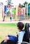 Disabled little boy in wheelchair watching children play on play