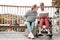 Disabled man sitting with colleague and working on laptop