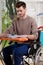 A disabled man sitting and ironing shirt