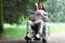 Disabled man sitting in wheelchair from behind hugs beautiful woman