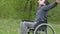 Disabled man thinks tired of break problems wheelchair with laptop in a wheelchair working on nature green background